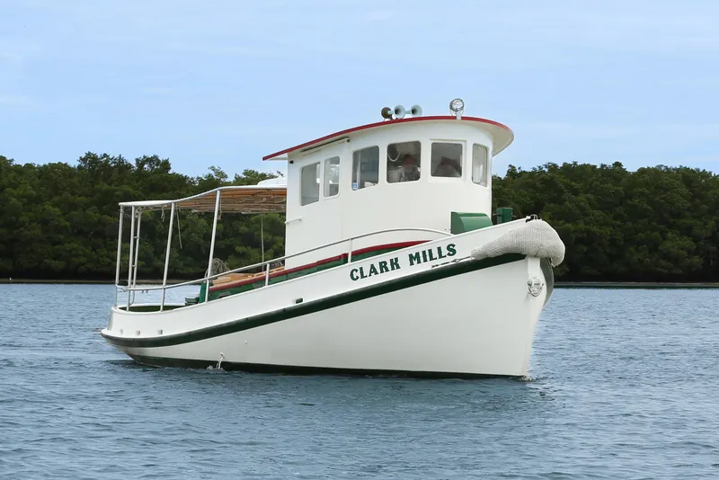 Slide: The Image of 1972 Mills Boat Works Tug Boat on calm water, surrounded by lush greenery. - 2