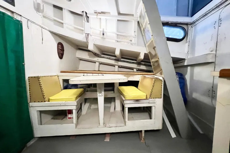 Slide: The Image of Interior of a 1972 Mills Boat Works Tug Boat with yellow-cushioned seating. - 20