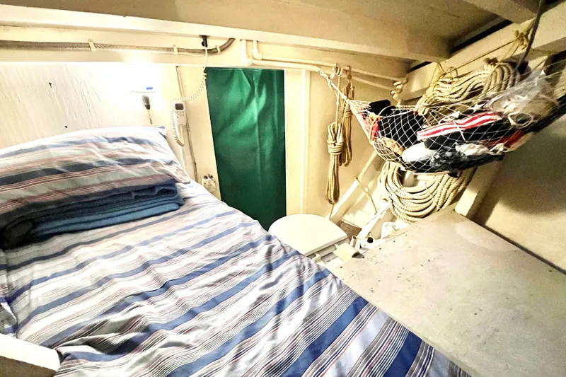 Slide: The Image of Cozy cabin interior of a 1972 Mills Boat Works Tug Boat with striped bedding. - 21