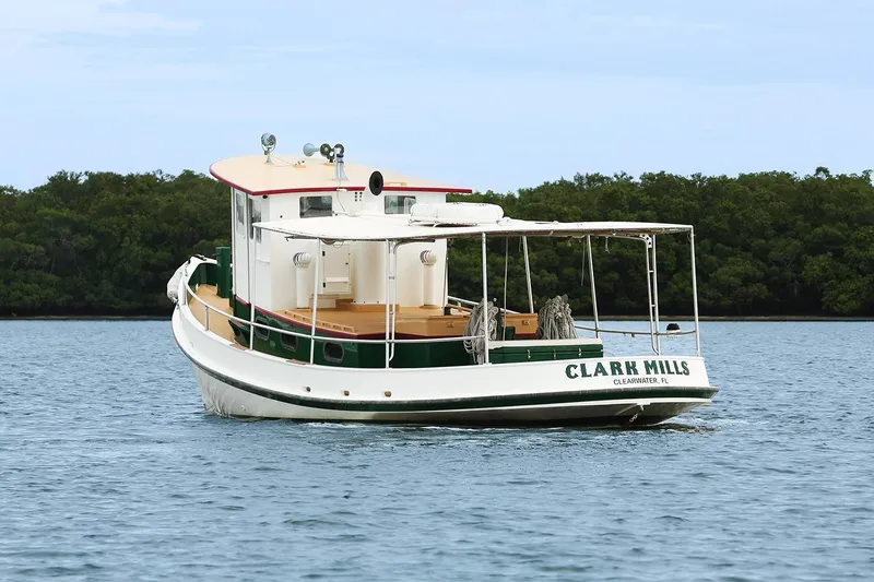 Slide: The Image of 1972 Mills Boat Works Tug Boat on calm water near lush green shoreline. - 4