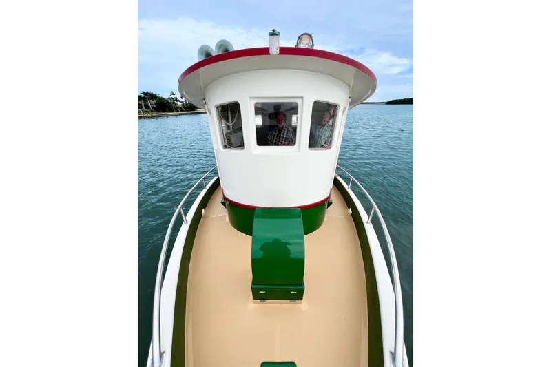 Slide: The Image of 1972 Mills Boat Works Tug Boat on calm water, featuring vibrant green and red accents. - 5