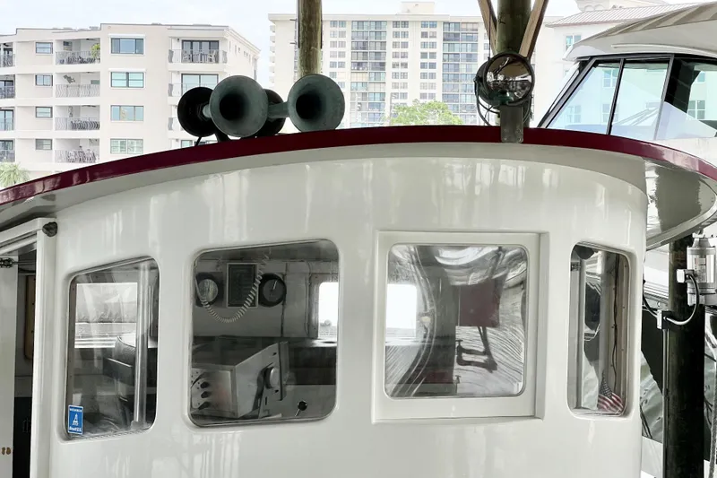 Slide: The Image of 1972 custom tug boat cabin with windows, docked near modern buildings. - 6