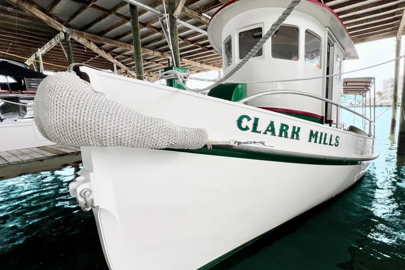 Slide: The Image of 1972 Mills Boat Works Tug Boat docked, named "Clark Mills," with white and green accents. - 7