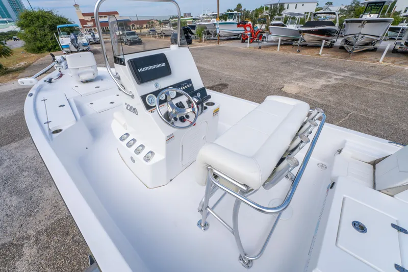 Slide: The Image of 2021 Blazer Bay 2200 boat interior with steering console and seating, parked in a marina. - 12
