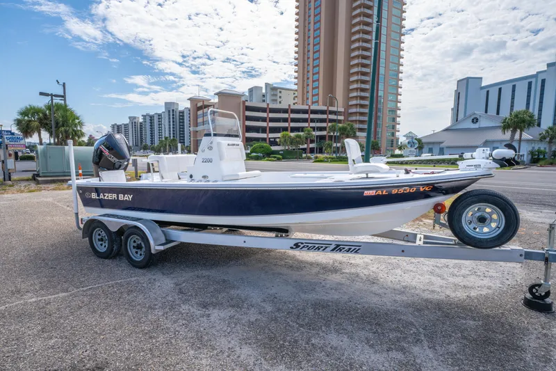 Slide: The Image of 2021 Blazer Bay 2200 boat on trailer, parked near high-rise buildings. - 6