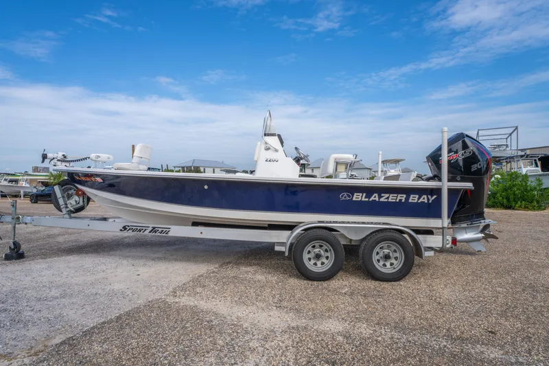 Slide: The Image of 2021 Blazer Bay 2200 boat on trailer, parked outdoors under a clear blue sky. - 8