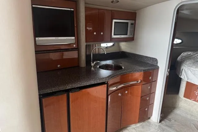Slide: The Image of 2006 Formula 40 Performance Cruiser kitchen with wood cabinets, sink, microwave, and TV. - 12