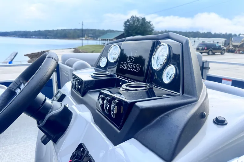Slide: The Image of 2026 Landau ISLAND BREEZE 21 dashboard with steering wheel, gauges, and cup holders by the water. - 11