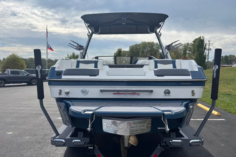 Slide: The Image of 2025 Malibu Wakesetter 22 MXZ boat, rear view, parked outdoors on a sunny day. - 7