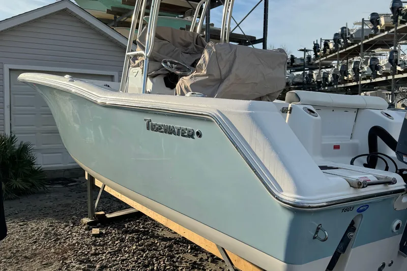 Slide: The Image of 2017 Tidewater 220 CC Adventure boat on display, light blue hull, parked outdoors. - 13