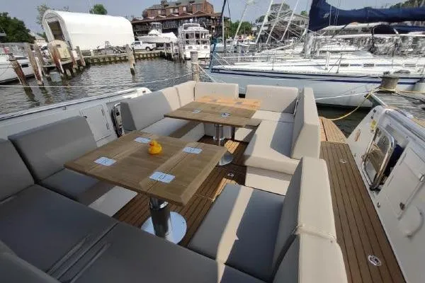 Slide: The Image of 2023 Fjord 41 XL yacht with spacious outdoor seating and wooden tables at a marina. - 23