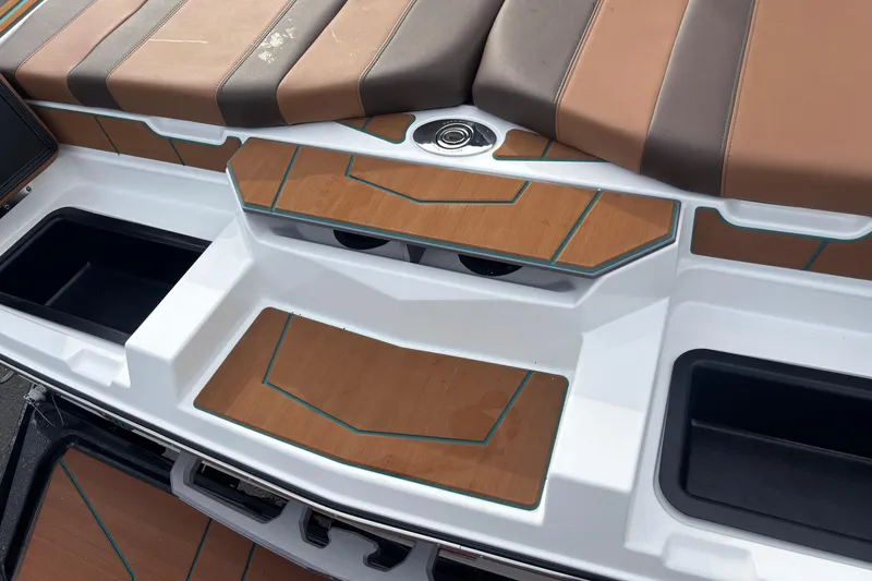 Slide: The Image of 2026 Malibu Wakesetter 21 LX boat interior with brown and gray seating, featuring storage compartments. - 7