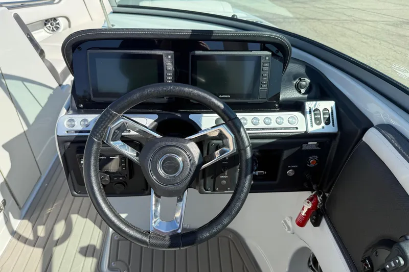 Slide: The Image of 2023 Crownline 290 SS boat dashboard with dual Garmin displays and steering wheel. - 10
