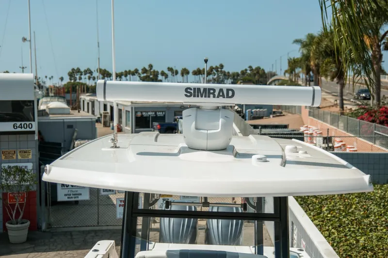 Slide: The Image of 2023 Robalo R270 Center Console boat with Simrad radar, docked near palm trees. - 19