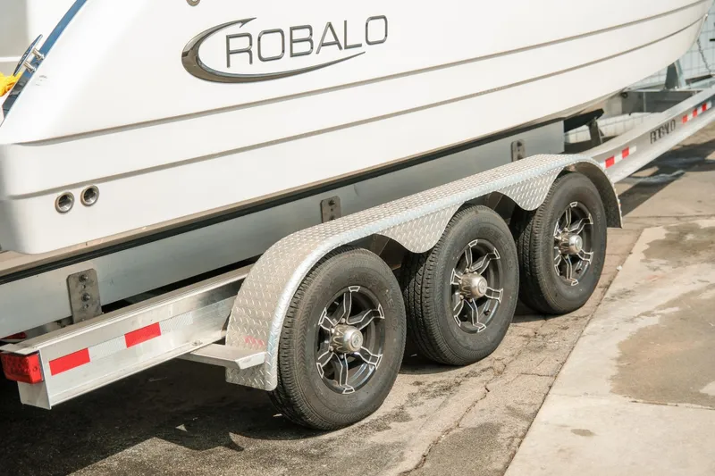 Slide: The Image of 2023 Robalo R270 Center Console boat on a triple-axle trailer. - 2