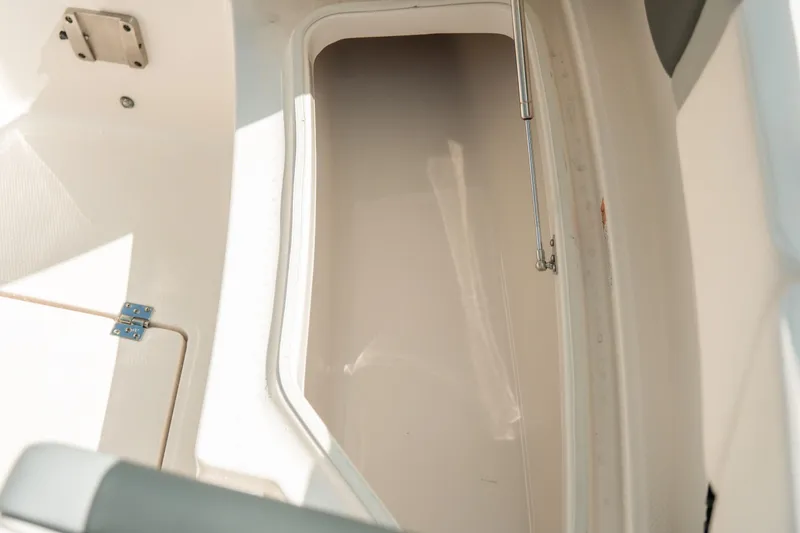 Slide: The Image of 2023 Robalo R270 Center Console storage compartment, open hatch, white interior. - 24