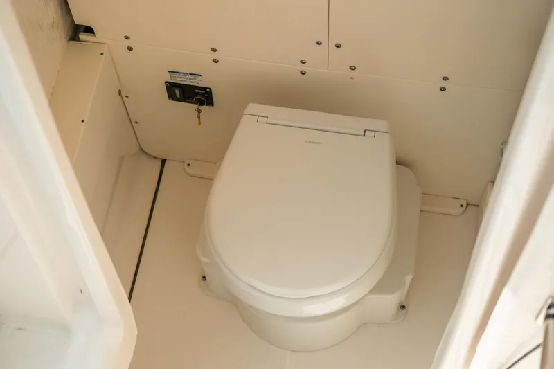 Slide: The Image of 2023 Robalo R270 Center Console boat interior with a compact marine toilet. - 31