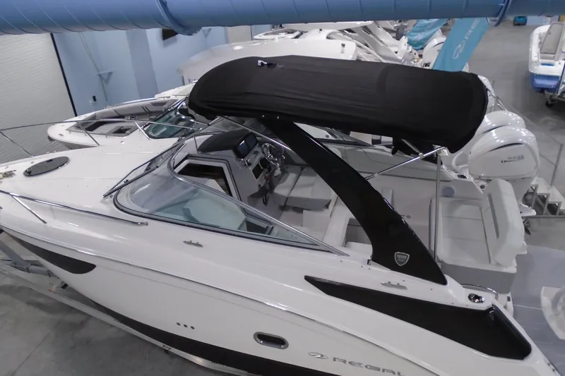 Slide: The Image of 2026 Regal 26 XO boat with black canopy in showroom setting. - 6