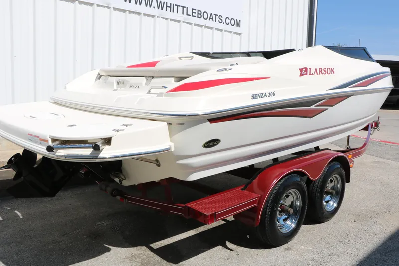 Slide: The Image of 2006 Larson 206 Senza boat on red trailer, parked near Whittle Boats dealership. - 2