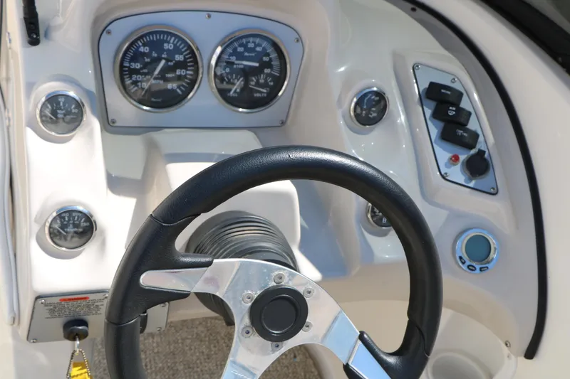 Slide: The Image of Steering wheel and dashboard of a 2006 Larson 206 Senza boat, featuring gauges and controls. - 25