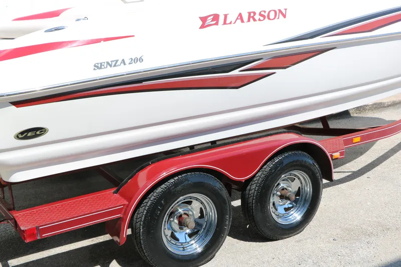 Slide: The Image of 2006 Larson 206 Senza boat on red trailer, featuring sleek design and VEC technology. - 32