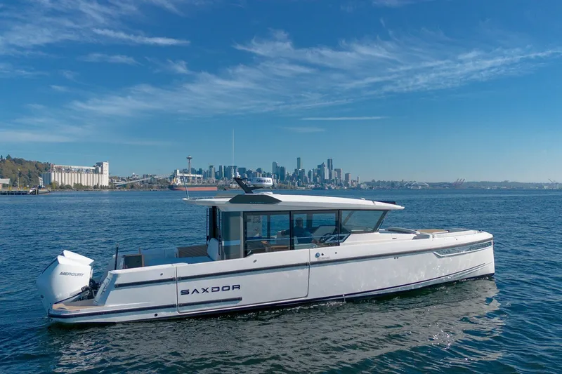 The Image of 2026 Saxdor 340 GTWA boat cruising on a sunny day with city skyline backdrop. - 0