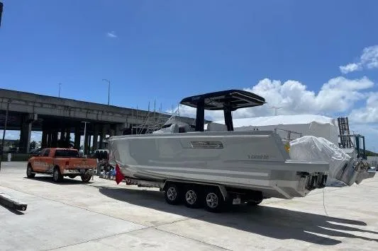 Slide: The Image of 2023 Fjord 38 Xpress boat on trailer, parked under clear blue sky. - 4