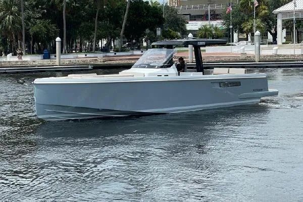Slide: The Image of 2023 Fjord 38 Xpress boat cruising on a calm waterway near a marina. - 45