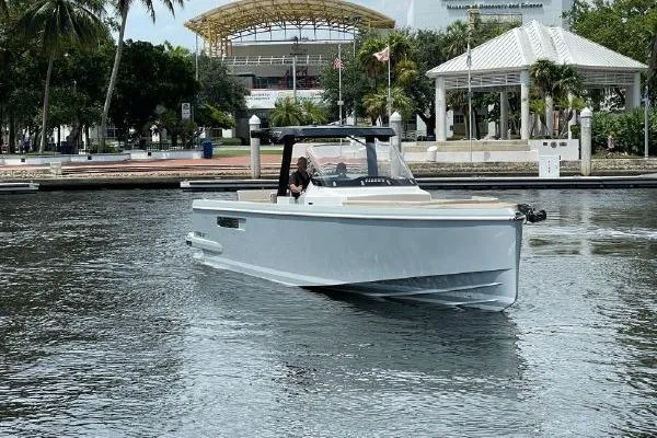 Slide: The Image of 2023 Fjord 38 Xpress boat cruising on a calm waterway near a marina. - 46