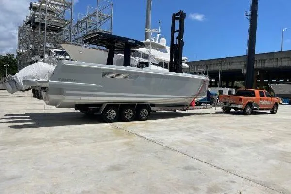 Slide: The Image of 2023 Fjord 38 Xpress boat on trailer, parked in marina with orange truck. - 6
