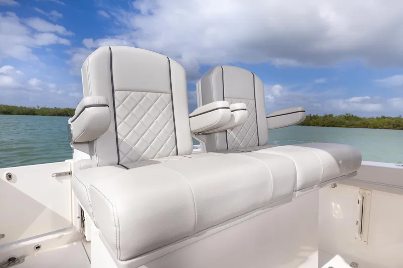 Slide: The Image of Manufacturer Provided Image: 2025 Pursuit S 248 Sport boat seats with quilted design, set against a scenic water backdrop. - 12
