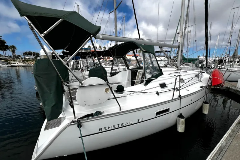 Slide: The Image of 2002 Beneteau 331 sailboat docked at marina, featuring green canopy and sleek design. - 12