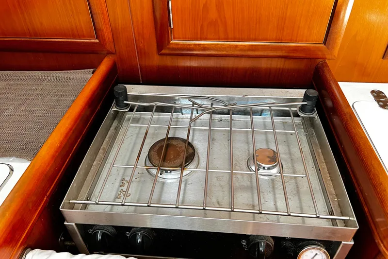 Slide: The Image of Stove in 2002 Beneteau 331 yacht kitchen, featuring two burners and wooden cabinetry. - 35