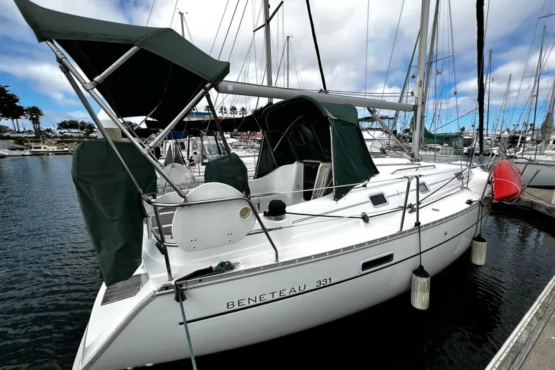 Slide: The Image of 2002 Beneteau 331 sailboat docked in marina, featuring green canopy and sleek design. - 4