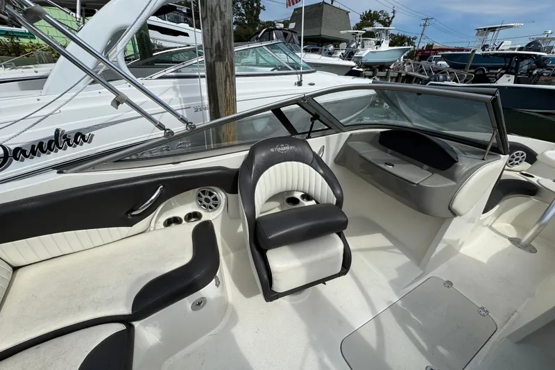 Slide: The Image of 2018 Stingray 204 LR boat interior with seating and dashboard, docked at marina. - 10