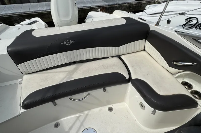 Slide: The Image of 2018 Stingray 204 LR boat interior with black and white seating, docked at marina. - 11