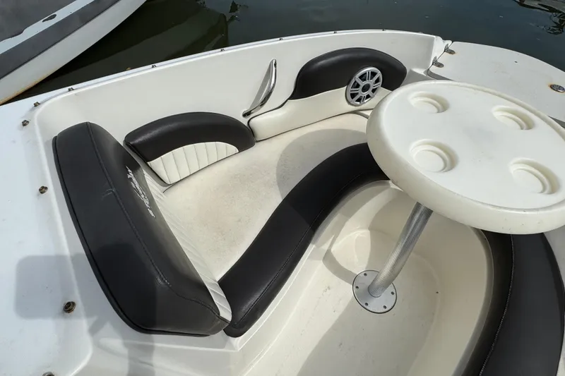 Slide: The Image of 2018 Stingray 204 LR boat interior with black and white seating and round table. - 16