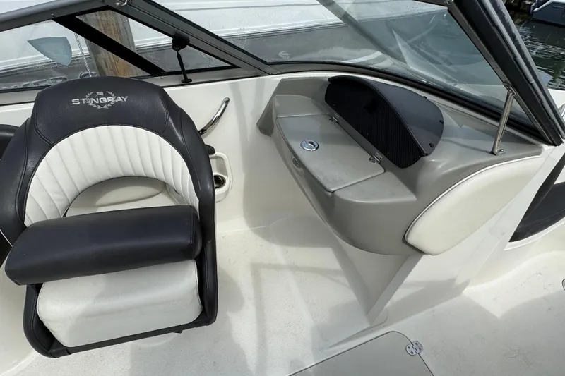 Slide: The Image of 2018 Stingray 204 LR boat interior with black and white seating and dashboard. - 5