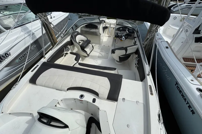 Slide: The Image of 2018 Stingray 204 LR boat interior with seating and steering wheel, docked among other boats. - 9