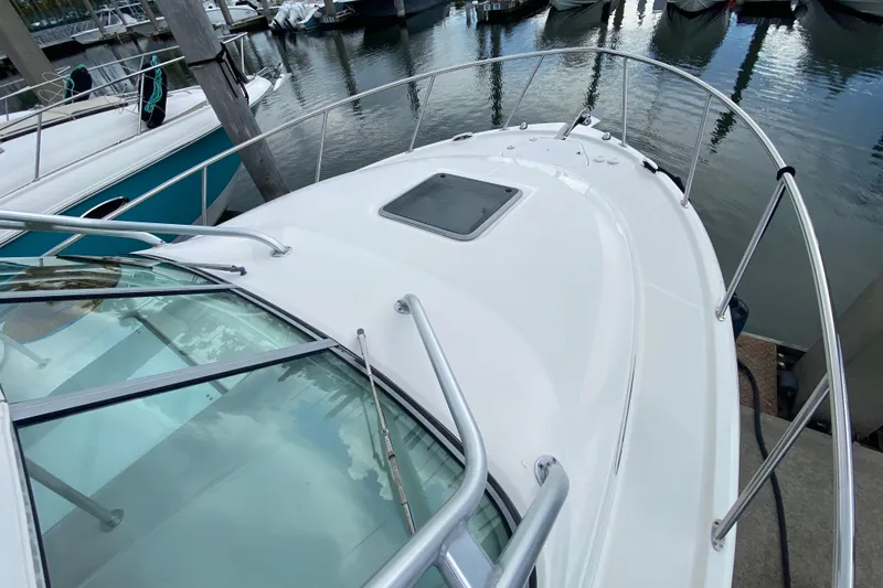 Slide: The Image of 2007 Robalo R305 Walkaround boat docked, featuring a white canopy and twin outboard engines. - 11