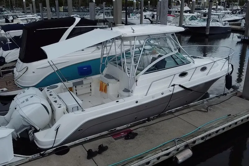 Slide: The Image of 2007 Robalo R305 Walkaround boat docked at marina, featuring dual outboard engines. - 9