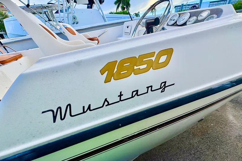 Slide: The Image of 2006 Century 1850 Mustang boat interior with seating and motor, docked near buildings. - 15