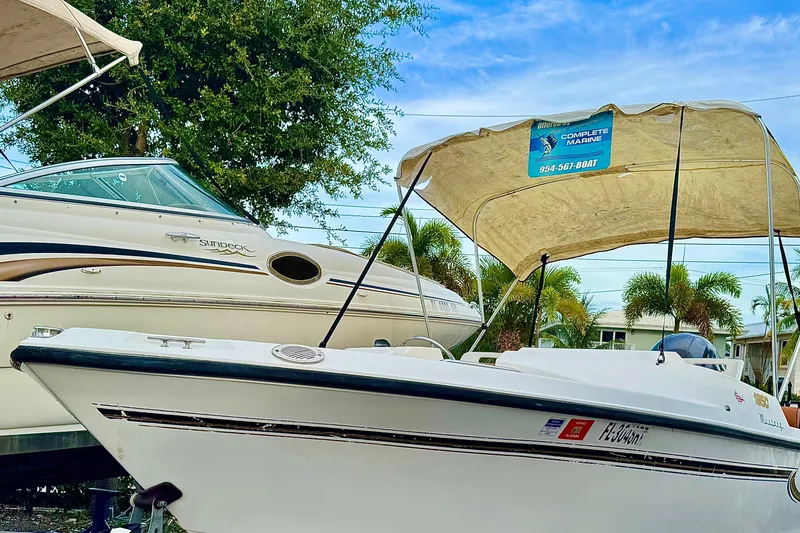 Slide: The Image of 2006 Century 1850 Mustang boat with outboard motor, parked near a fence. - 16