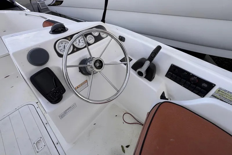 Slide: The Image of 2006 Century 1850 Mustang boat interior with seating and storage, displayed at a marina. - 40