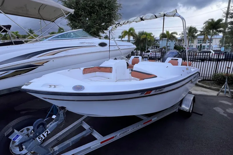 Slide: The Image of 2006 Century 1850 Mustang boat with powerful outboard motor, parked near black fence. - 46