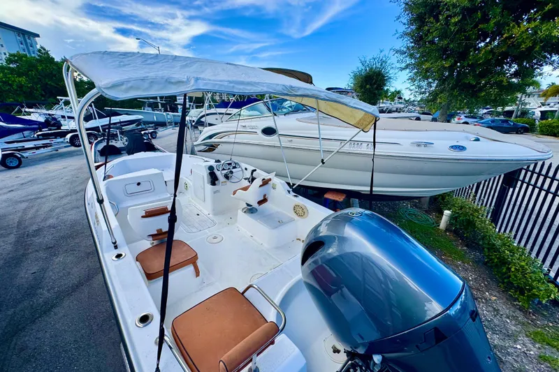 Slide: The Image of 2006 Century 1850 Mustang boat interior with seating and steering wheel, docked near other boats. - 5