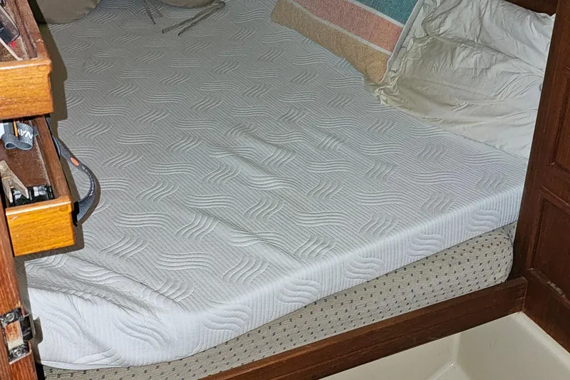 Slide: The Image of Cozy cabin bed in 2000 Island Packet 350 sailboat with patterned mattress and wooden storage. - 15