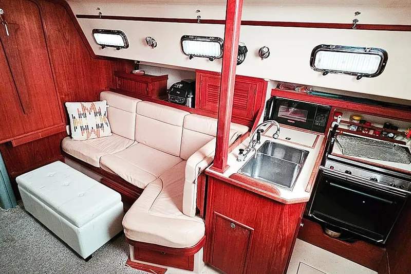 Slide: The Image of Interior of 2000 Island Packet 350 sailboat with cozy seating and compact kitchen area. - 6