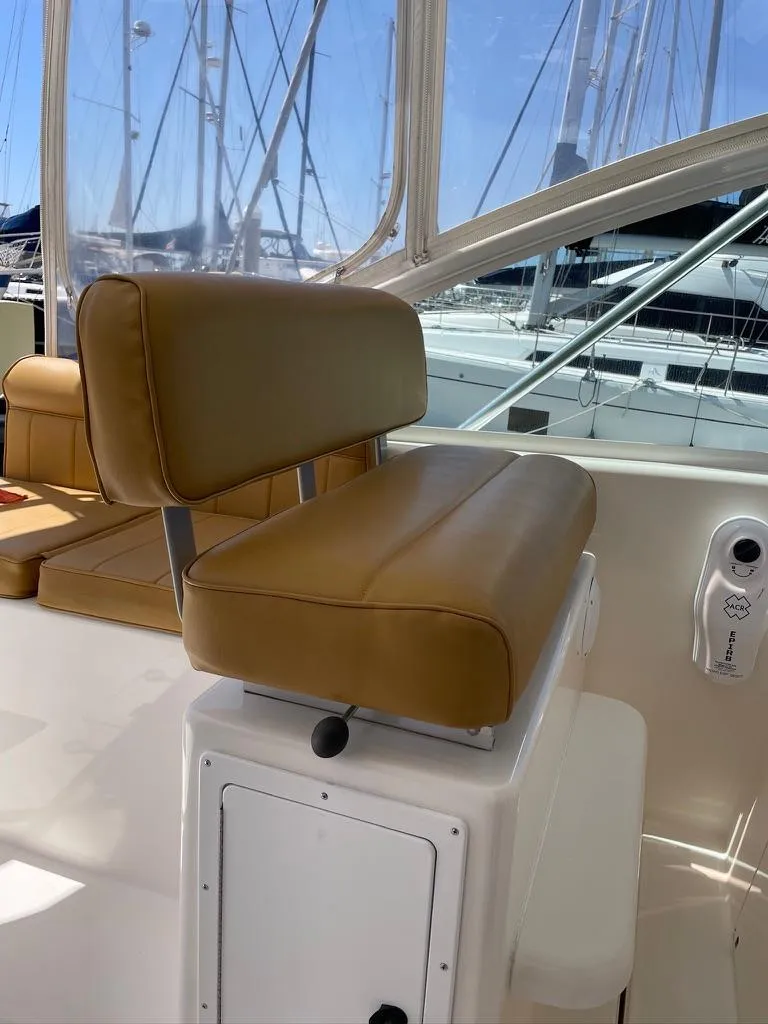Slide: The Image of 2004 Cabo 35 Express boat with tan leather seating and marina background. - 26