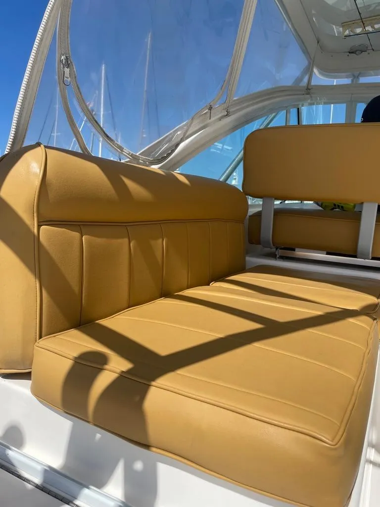Slide: The Image of Tan leather seating on a 2004 Cabo 35 Express boat under clear blue skies. - 28